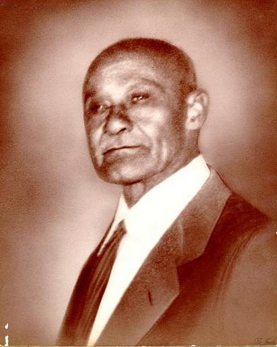 Sepia studio portrait of Warren Prater in a dark suit, white shirt and tie